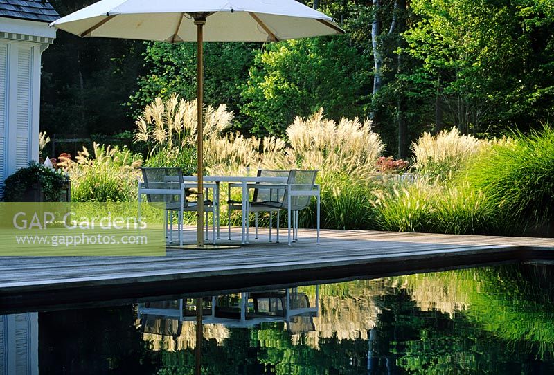 Terrasse en bois avec mobilier et parasol par étang réfléchissant