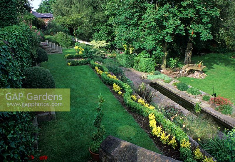 Jardin en terrasses avec parterres de fleurs, canal et marches