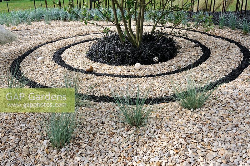 Spirale de basalte noir concassé dans un jardin de gravier avec Ophiophogon au centre - RHS Tatton Park Flower Show
