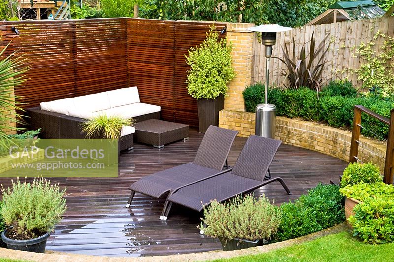 Terrasse en bois avec mobilier moderne et chauffe-terrasse dans un jardin urbain. Lavandula - Lavande en pot. Muswell Hill, Londres