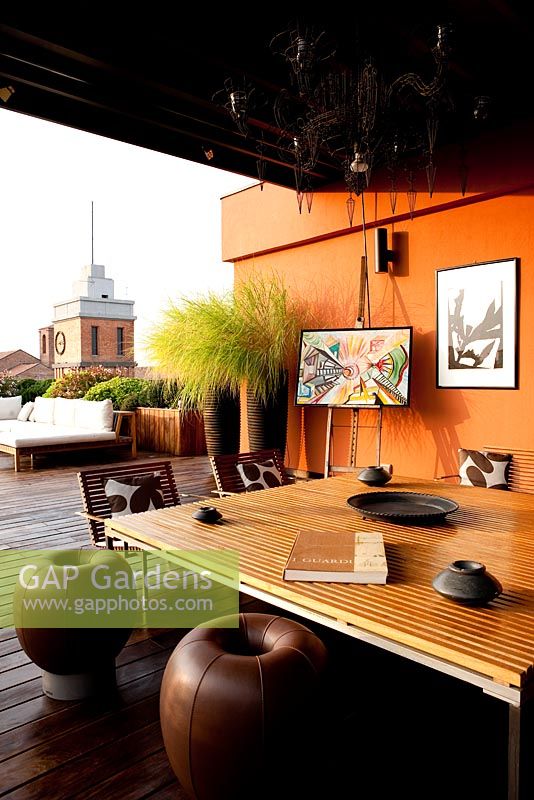 Terrasse avec coin salon contemporain avec canapés et murs peints en orange à Ferrare, Italie