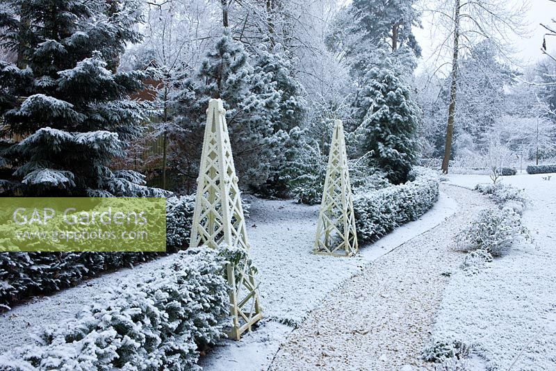 Jardin de ville formelle avec des obélisques en bois recouverts de neige, Oxford, UK.