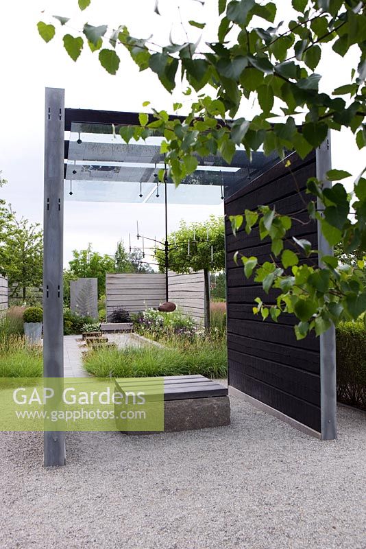 Coin salon sous structure en verre et bois dans un jardin moderne minimal