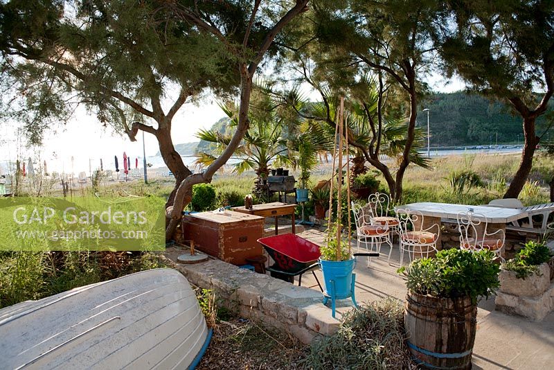 Patio dans le jardin côtier méditerranéen avec vieux bateau de pêche