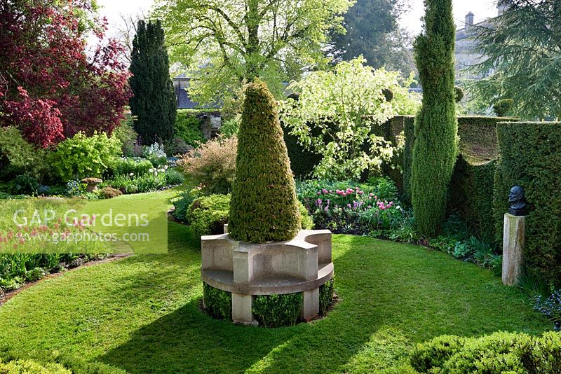 Le Cottage Garden avec siège en pierre entourant un if anglais topiarisé, Highgrove Garden, mai 2009.