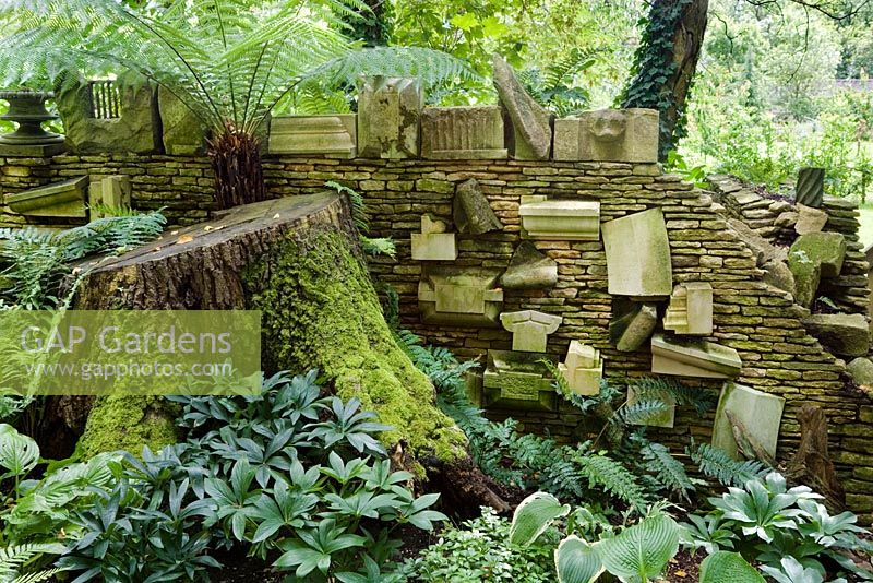 Le 'Mur des cadeaux' dans le Stumpery composé de divers morceaux de pierre architecturale, dont certains ont été donnés à SAR le Roi, d'autres qu'il a collectés. Le Stumpery est basé sur un concept victorien de fougères croissantes parmi les souches d'arbres. Jardin de Highgrove, août 2007.