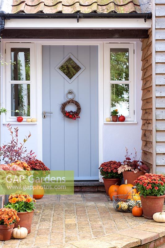 Décoration de porte d'entrée décorée pour l'automne avec des courges, des citrouilles, des chrysanthèmes