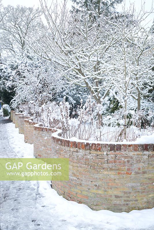 Mur de jardin en serpentine avec de la neige. Mur de manivelle froissé.