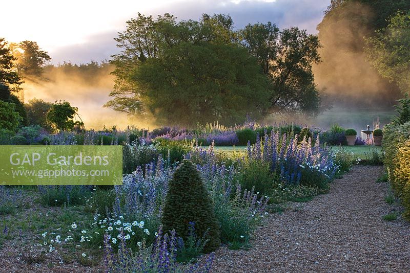 Lumière de l'aube sur le fleuve nar et le jardin de gravier devant le hall. Jardins de Narborough Hall, Norfolk