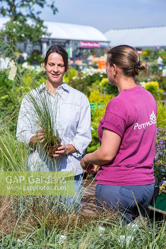 Clientèle recevant des conseils sur les herbes, d'un employé d'un centre de jardinage