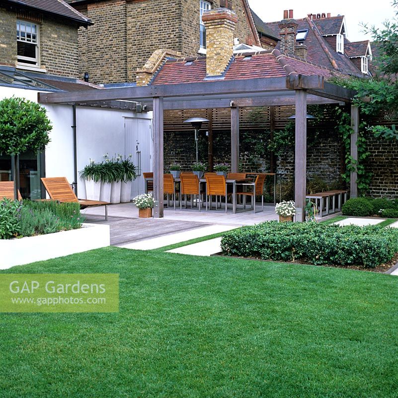 La terrasse en bois relie la maison au jardin avec un coin repas extérieur