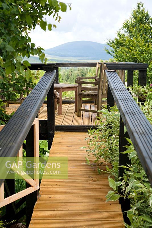 Coin salon sur une plate-forme de terrasse en bois surélevée avec vue sur les collines