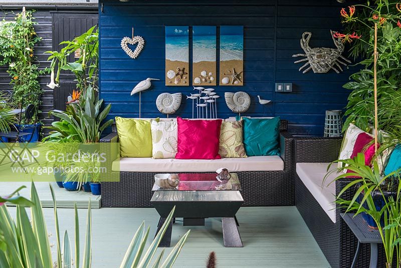 Un coin salon couvert avec des décorations inspirées de la mer, un canapé et une table.