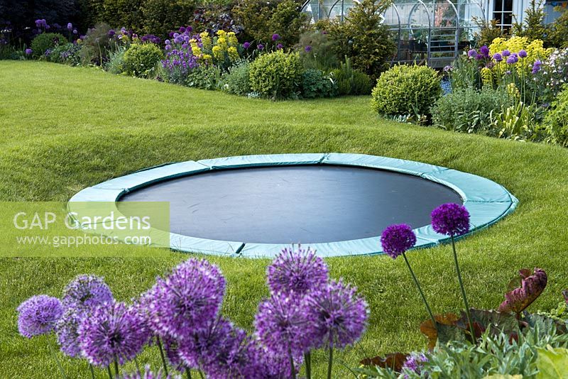 Un trampoline installé dans un cercle de pelouse surélevé de façon à ce qu'il soit largement caché à distance.