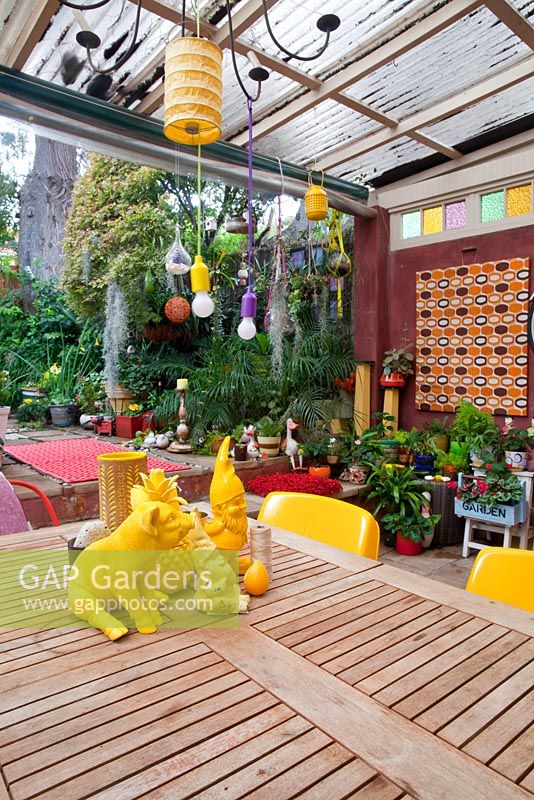 Le jardin du centre-ville avec des bégonias et des spathiphyllums présente des pièces rétro éclectiques colorées provenant des marchés locaux, y compris une salle à manger en bois avec des objets jaunes assortis