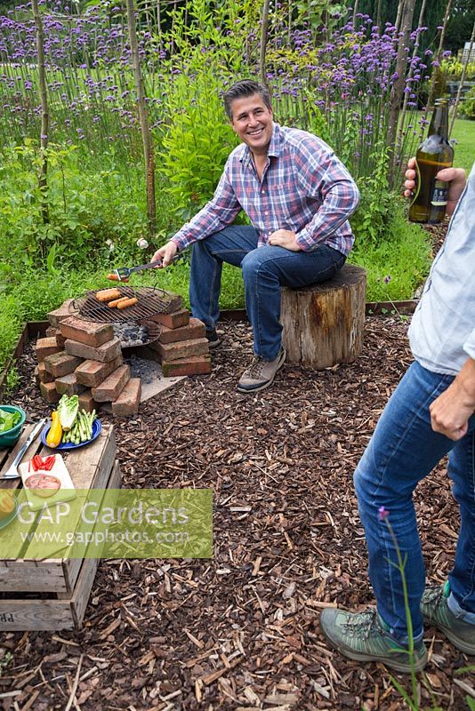 Un homme cuisine des saucisses sur un barbecue fait maison