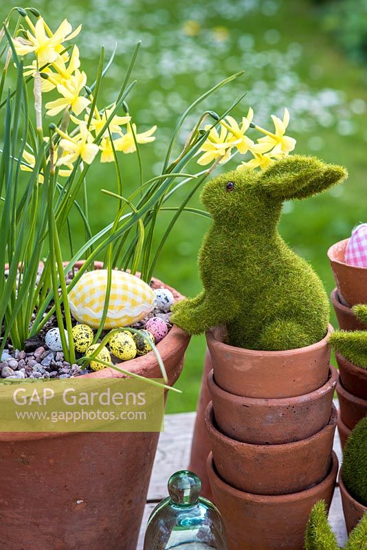 Lapins de Pâques jouant dans des pots en terre cuite avec des œufs et des fleurs