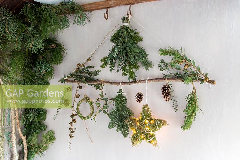 Décorations de Noël en matériau naturel - branche décorée d'étoiles, guirlande, feuillage et lumières LED dans un cadre rustique