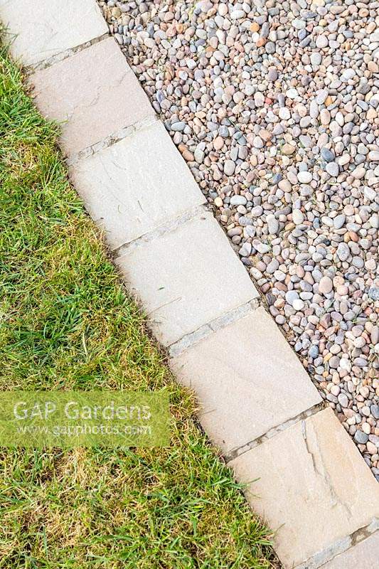 Chemin de jardin en gravier incurvé avec du gravier 'Scottish Pebbles' et bordé de pavés de grès en 'Castle Grey' contre une pelouse