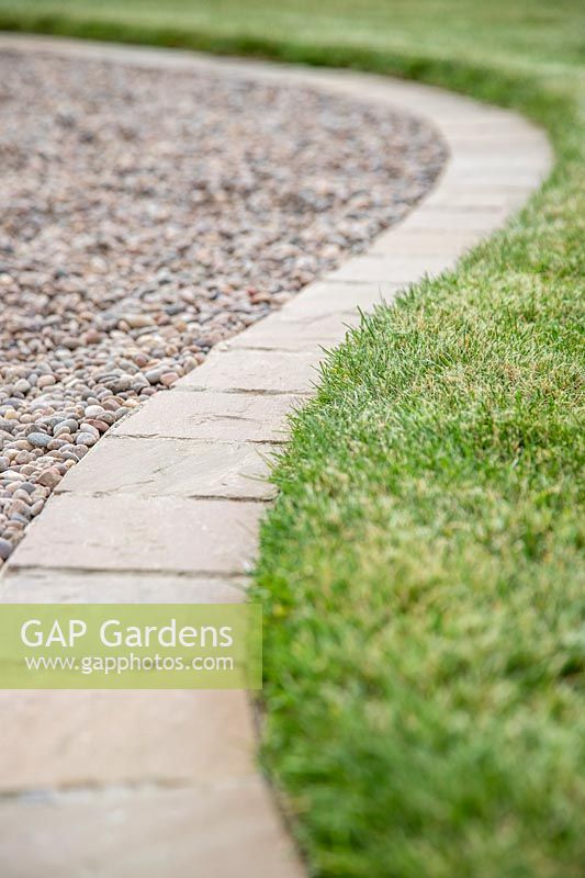 Bordure de chemin en pavés carrés, bordure entre pelouse et chemin de gravier.