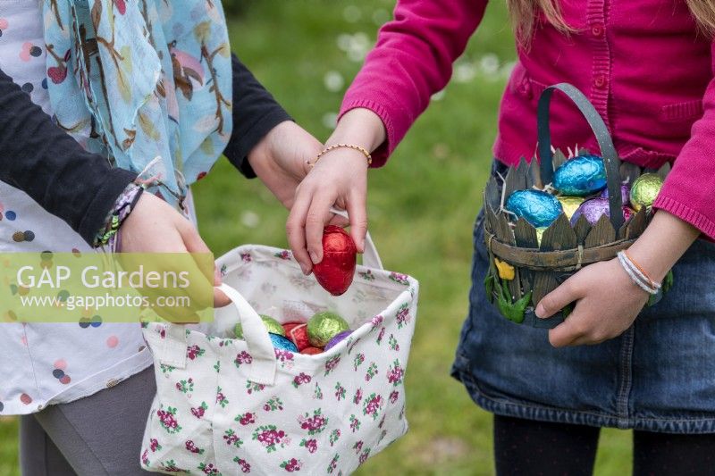 Enfants collectant des œufs en chocolat colorés dans des paniers à Pâques
