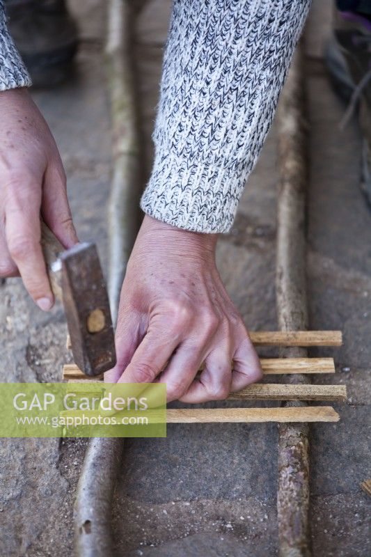 Faire une bordure de parterre de fleurs en palissade à l'aide de bâtons de noisetier et de bois d'allumage.