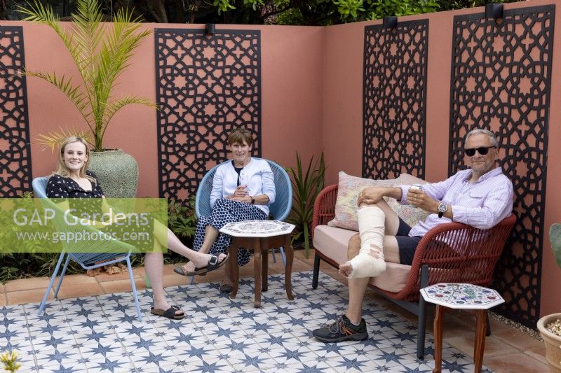 Couple de détente avec leur fille dans leur jardin patio de style marocain