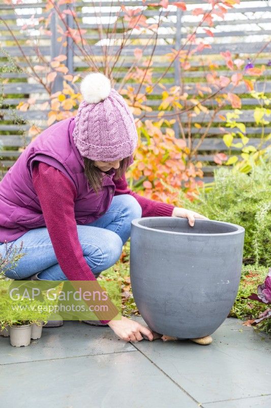 Femme plaçant des pierres sous le pot pour aider au drainage