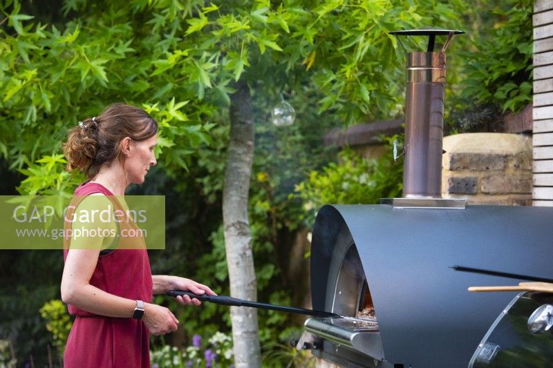 Lisa, propriétaire du jardin, prépare des pizzas dans le four à pizza extérieur.