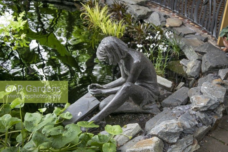 Sculpture féminine en bronze assise au bord de l'étang du jardin de Hamilton House en mai