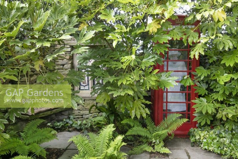 La reine dans une cabine téléphonique rouge dans la folie - un coin salon ombragé au jardin de Hamilton House en mai