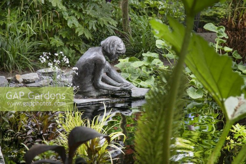 Sculpture féminine en bronze assise au bord de l'étang du jardin de Hamilton House en mai