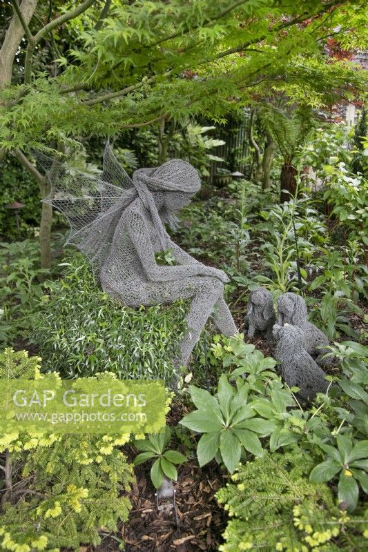 Fil sculpture d'une fée avec trois petits chiens par Derek Kinsett à Hamilton House garden en mai