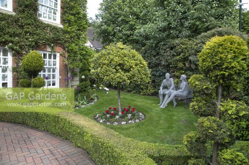 Jardin de devant avec des sculptures en fil de fer de Derek Kinzett et des arbres nuageux au jardin de Hamilton House en mai