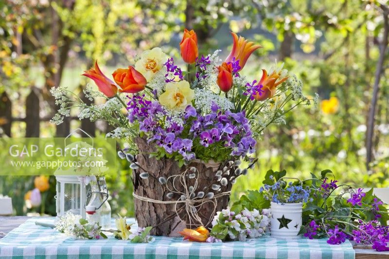 Arrangement de fleurs de printemps avec des jonquilles, des tulipes, des pensées, des myosotis et des branches de fleurs de pommier.
