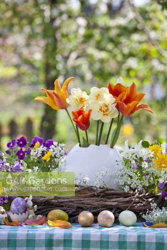 Arrangement de table de Pâques avec des œufs colorés et des fleurs printanières.