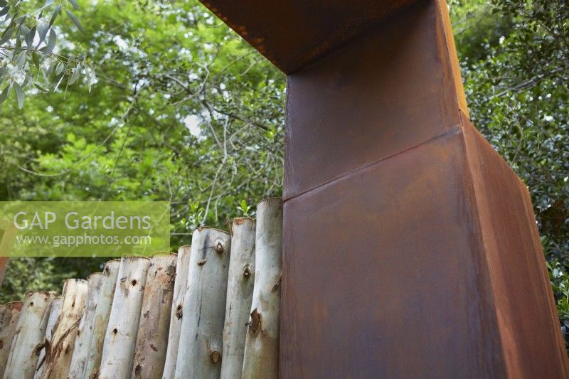 Structure de jardin en acier Corten avec clôture en bois d'eucalyptus. Été.