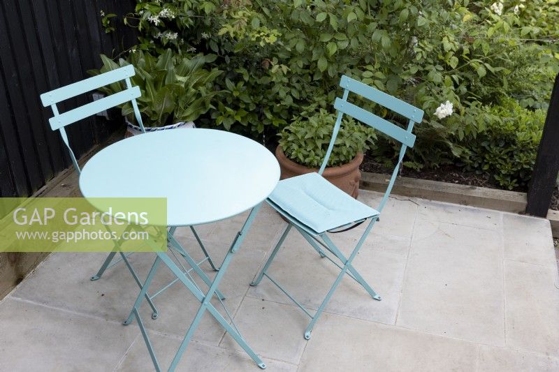 Table circulaire peinte en vert avec des chaises sur un patio isolé
