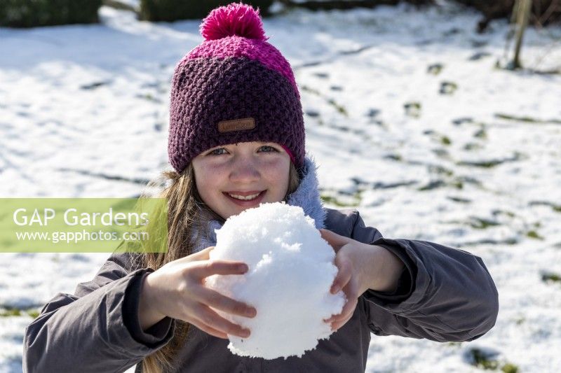 Petite fille tenant une boule de neige dans ses mains