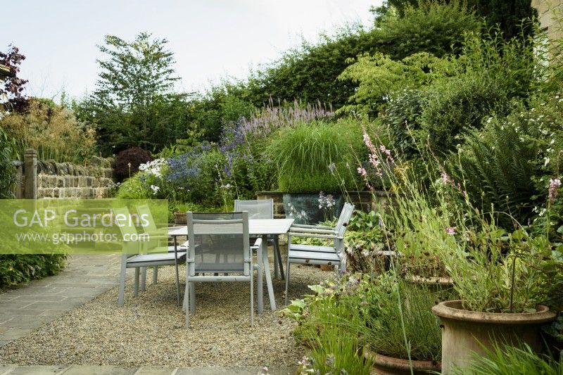 Jardin de la cour avec coin repas entouré de pots et de parterres surélevés à Cow Close Cottage, North Yorkshire en juillet