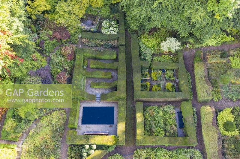 Vue sur une grande surface de haies formelles d'ifs taillés contenant des 'chambres' de jardin, y compris un bassin réfléchissant. Juillet. Image prise depuis un drone.