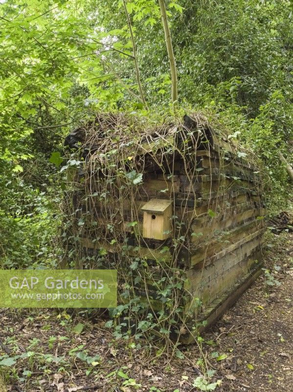 Hôtel d'insectes fabriqué à partir de vieilles planches de bois avec nichoir dans un jardin boisé