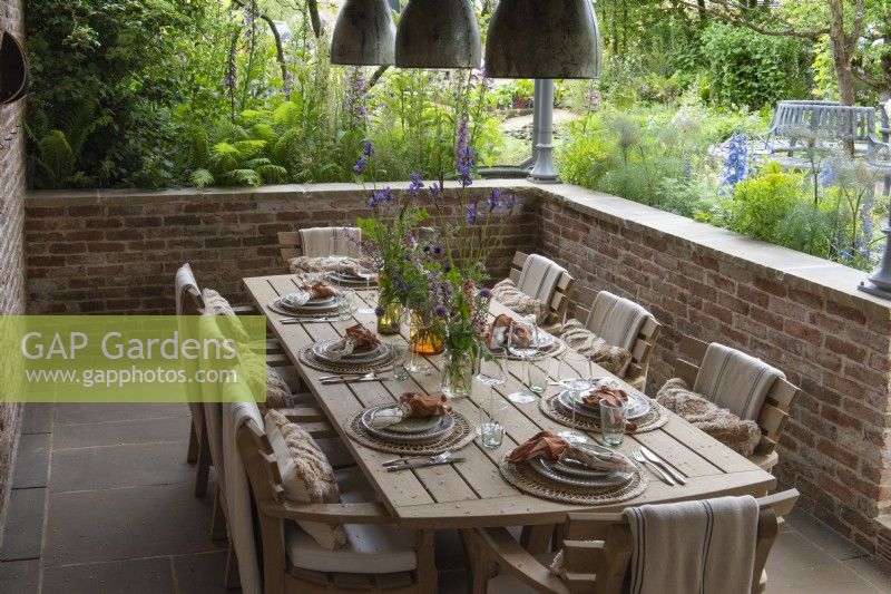Une salle à manger en contrebas surplombe un potager saisonnier rempli de plantes comestibles et ornementales.
