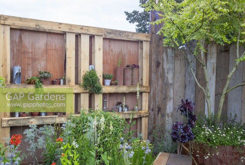 Clôture de jardin fabriquée à partir de planches d'échafaudage en bois de récupération et de palettes en bois utilisées comme étagères et plantation résistante à la sécheresse - Punk Rockery Garden