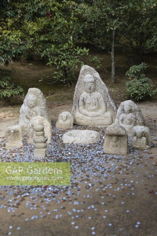 Groupe de bouddhas en pierre avec des pièces de monnaie au sol comme offrandes. 
