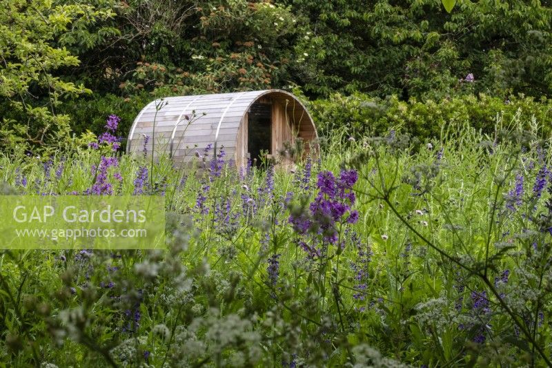 Sauna en bois installé dans une prairie de fleurs sauvages vivaces. 