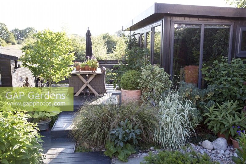 Jardin contemporain avec terrasse en bois et bureau de jardin 