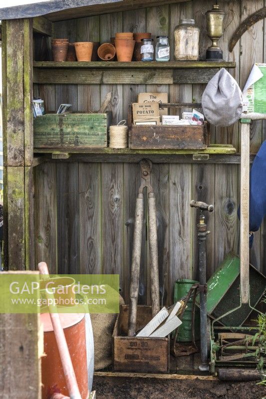 Abri de jardin intérieur avec de vieux outils de jardin, des pots en argile et des caisses en bois vintage avec des livres de jardinage 