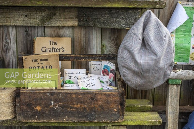 Boîte en bois antique dans un abri de jardin contenant des livres de jardinage vintage et des sacs de graines 