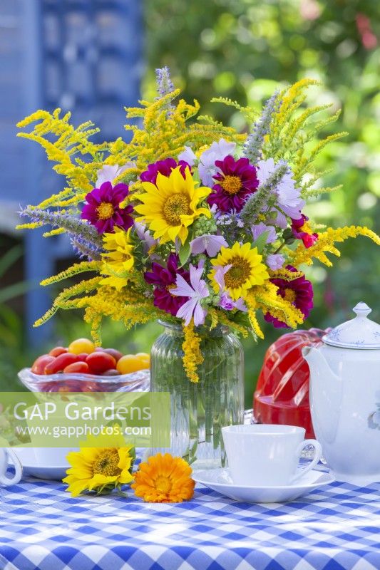 Bouquet d'été avec tournesols, Dahlia, Solidago, Agastache et Malva sur la table dressée pour un thé. 